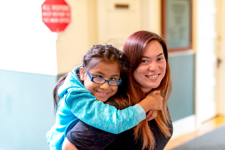 Image of an adult and child smiling and hugging